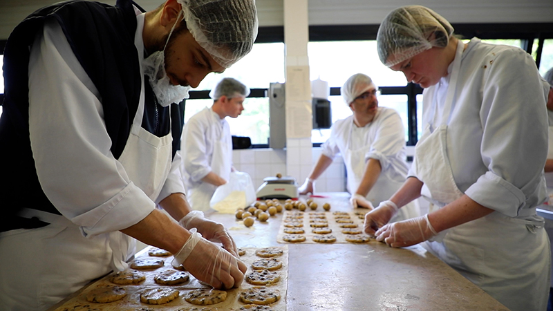 Photo de l'équipe de la biscuiterie de l'ESAT Sésame services (VYV3 Pays de la Loire) situé à La Montagne à côté de Nantes - Loire Atlantique, en train de confectionner des cookies